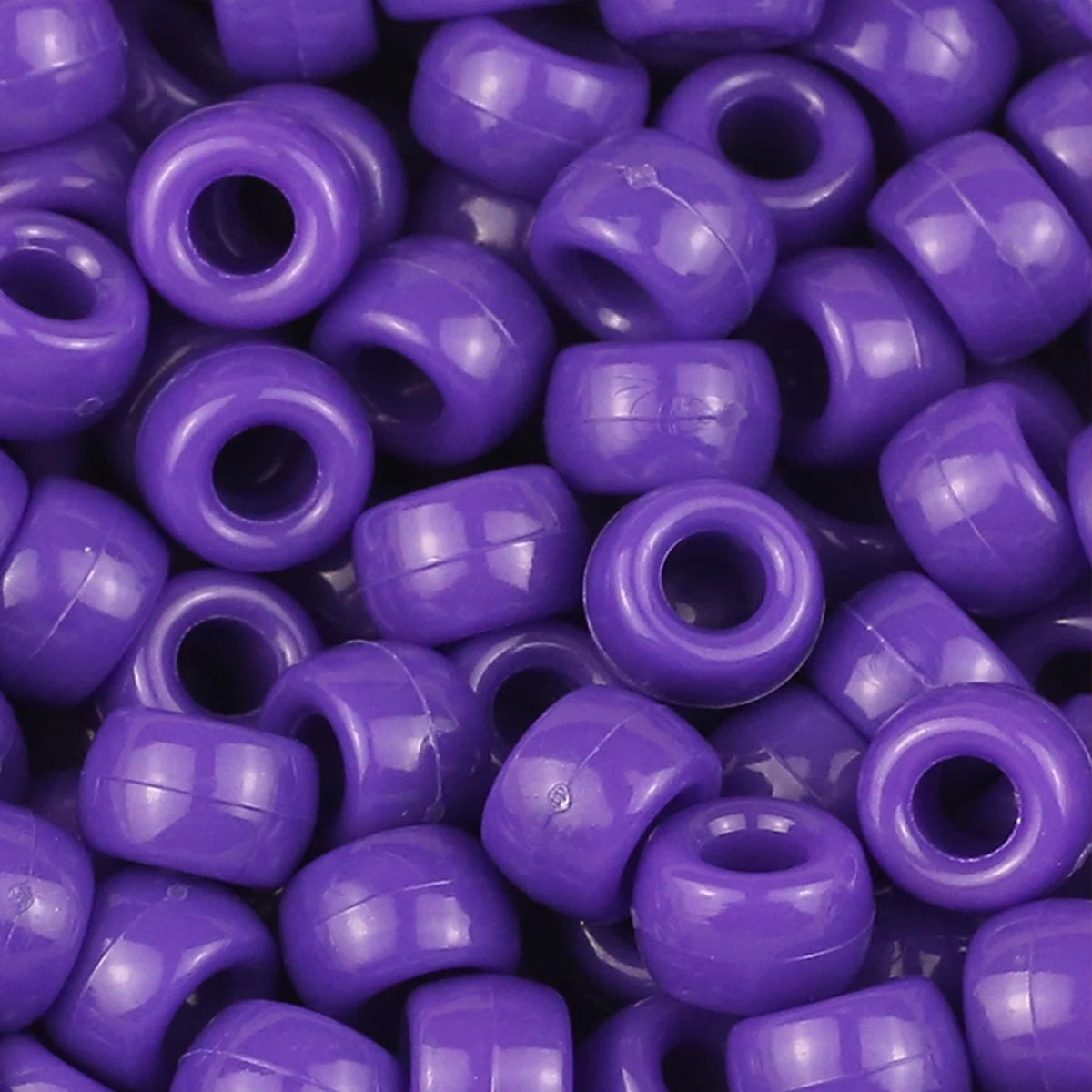 A close-up view of small, solid purple pony beads for jewelry making and craft projects.