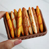 A basket filled with several golden-brown baguette-shaped bread loaves.