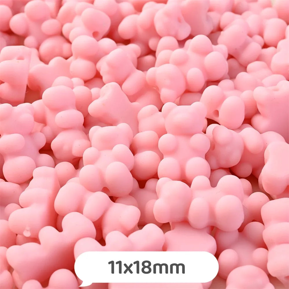 Pink bear-shaped acrylic craft beads with a shimmer finish in a pile