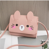A pink cat-face mini PU leather crossbody handbag with long ears and whiskers resting on a gray surface.