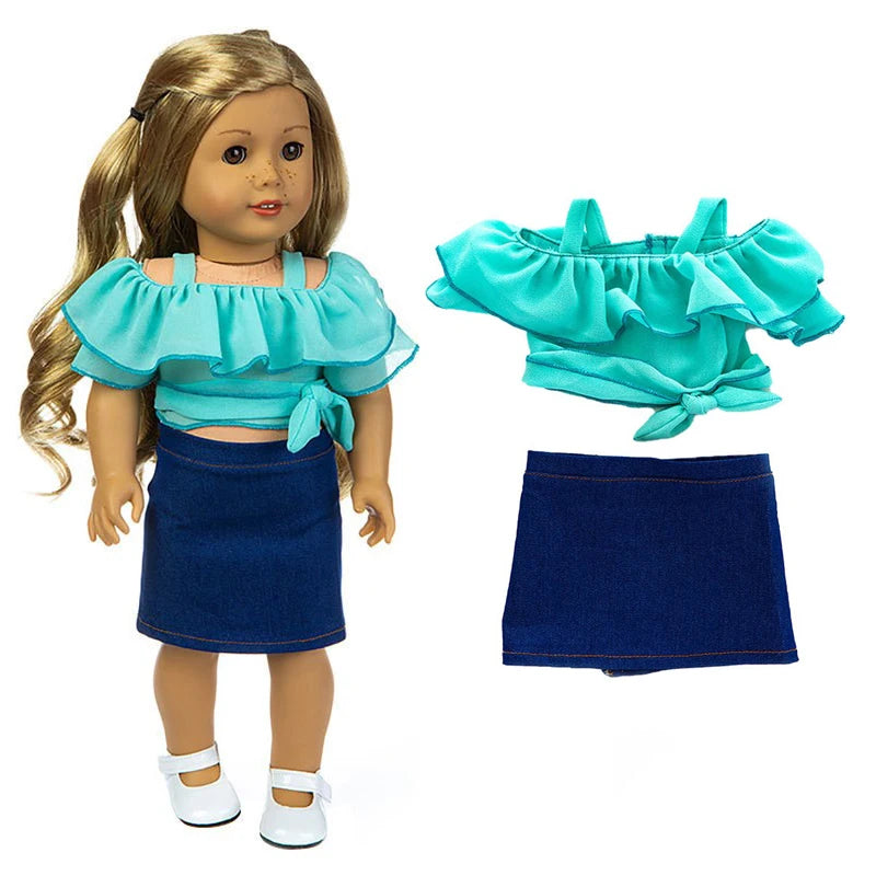 A doll wearing a turquoise ruffled blouse, navy skirt, and white shoes, with the matching top and bottom pieces displayed sep
