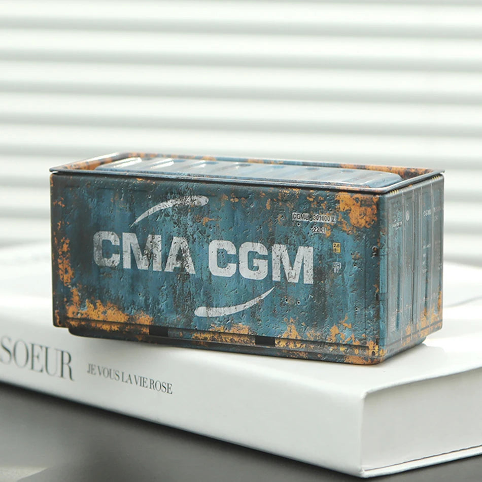 A miniature industrial iron storage box with an openable lid, showing weathered blue and orange metal.