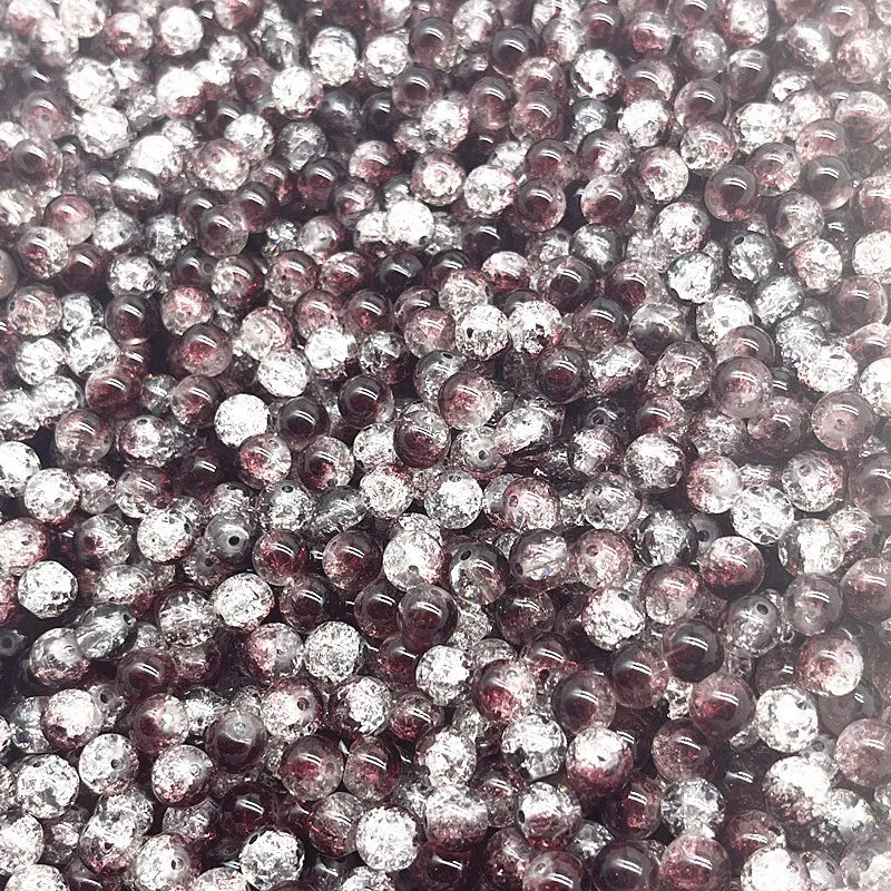 A close-up view of small, round glass crackle beads in shades of purple and clear.