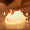 A glowing white silicone rabbit night light with touch sensor resting on a surface.