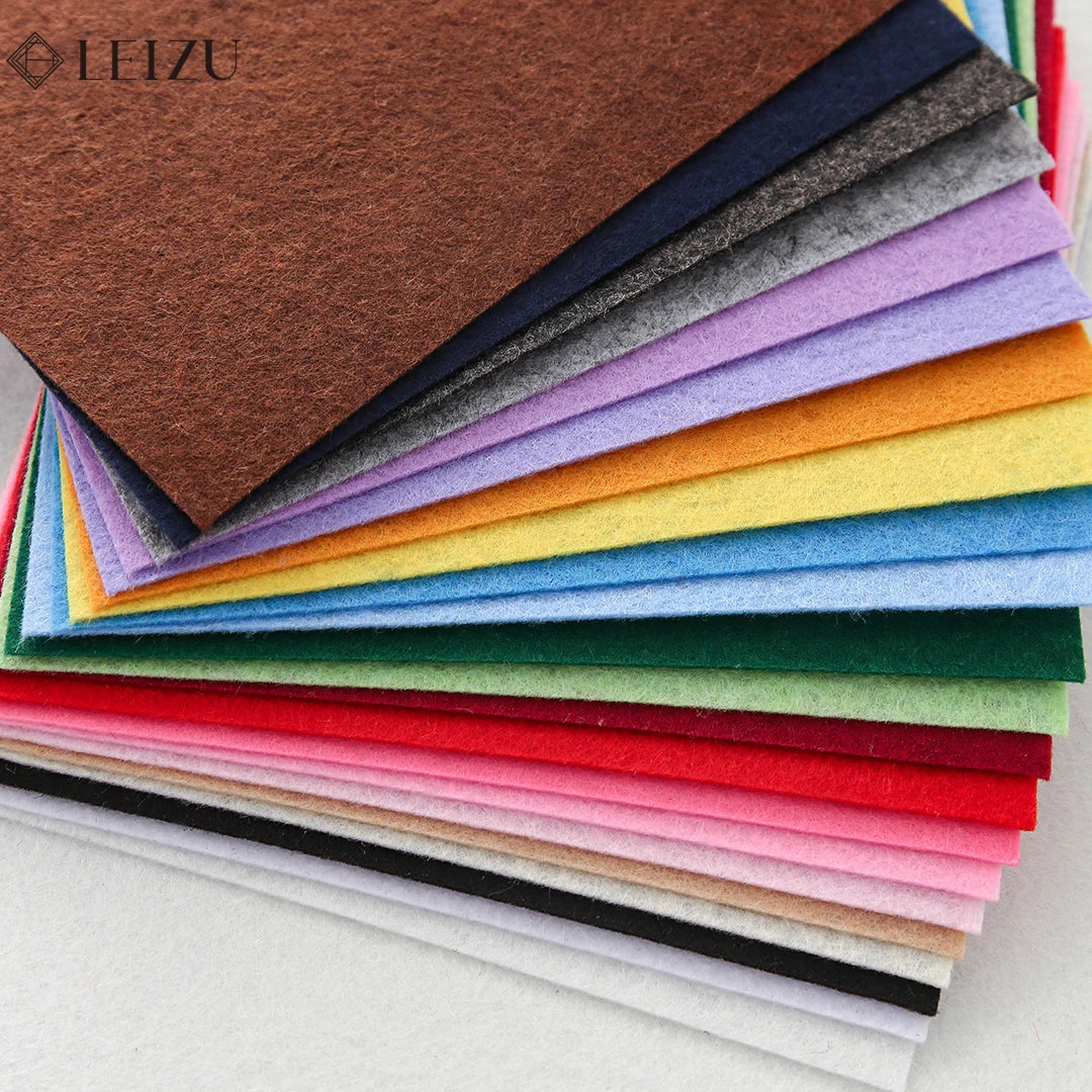 A stack of colorful non-woven felt fabric sheets in various shades of brown, blue, green, yellow, pink, and red.
