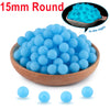 A wooden bowl filled with bright blue glow in the dark silicone beads, some loose beads are shown below.