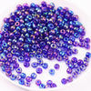 A pile of iridescent purple and blue glass rice beads for DIY jewelry and crafting.