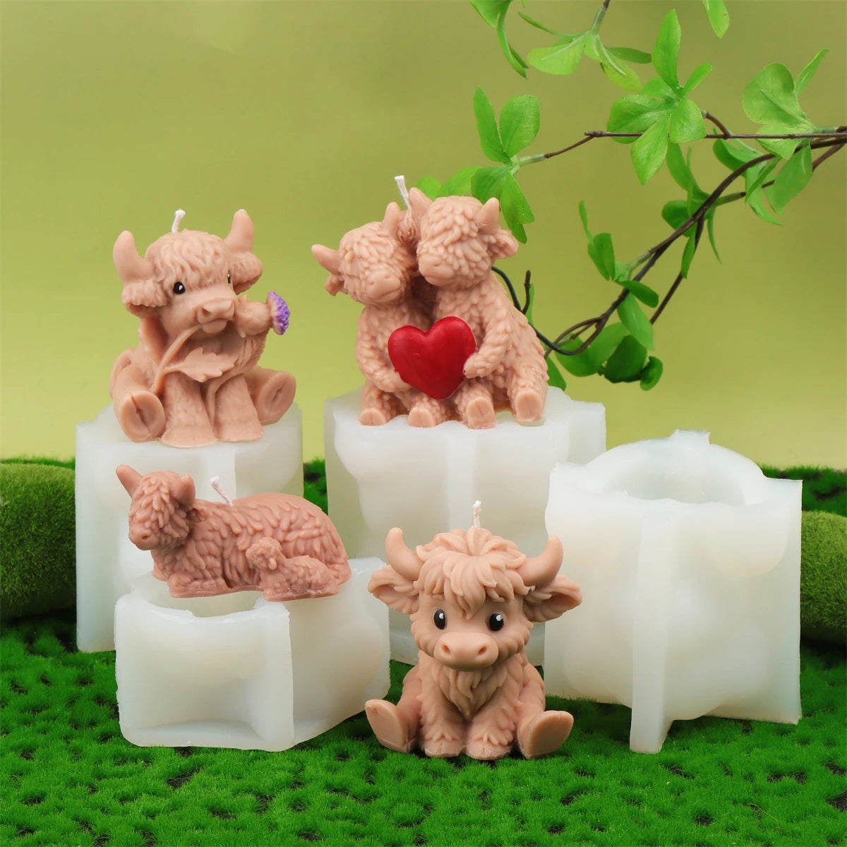 A set of four silicone candle molds shaped like Highland cows in various shades of pink and brown resting on green moss.