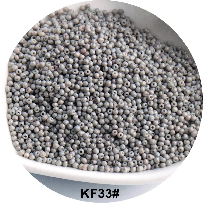 A pile of small, round, gray glass seed beads is shown in a white bowl.