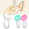 A hand is shown squeezing a clear manual breast pump for milk expression, with two similar pumps displayed below.