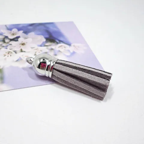 Silver velvet tassels with gray stripes resting on a purple floral background.