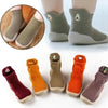A collection of soft-soled baby first walker socks and shoes in various earthy tones including beige, olive green, orange, an