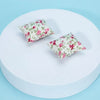 A pair of floral patterned fabric pillows displayed on a white circular surface.