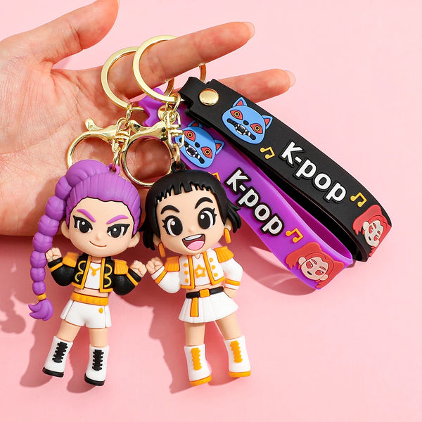 Un couple de porte-clés Kpop Rumi avec des personnages féminins stylisés en tenues violettes et oranges.