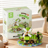 A box of a miniature forest cabin building block set featuring a greenhouse and windmill model.