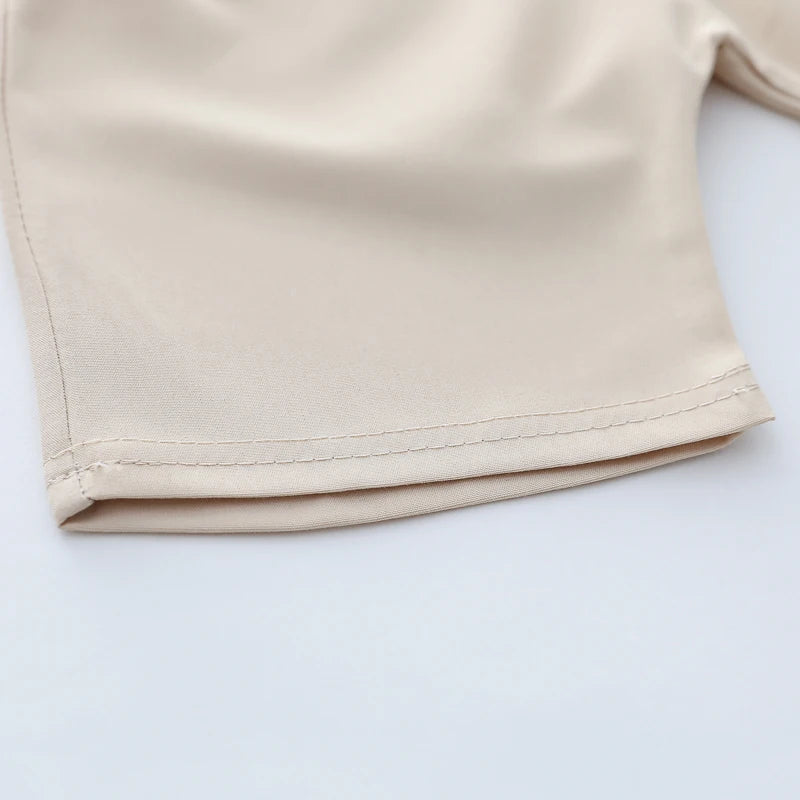 A close-up of a light beige summer cartoon bear embroidered polo shirt sleeve.
