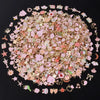 A close-up view of assorted metal pendants and charms in various pink, gold, and iridescent colors.