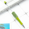 A green beaded ballpoint pen craft kit with a metal tip rests on a white surface next to a book.