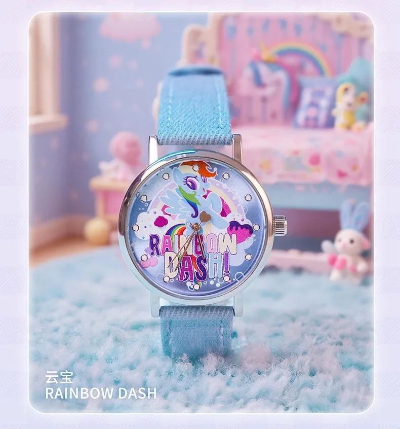 A blue wrist watch with a rainbow design and a light blue strap is displayed in a soft, pastel-colored setting.