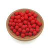 A wooden bowl filled with numerous small, round red silicone beads for jewelry making and crafts.
