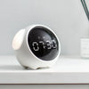 A white digital alarm clock with a round display showing 07:30 sits on a white surface.