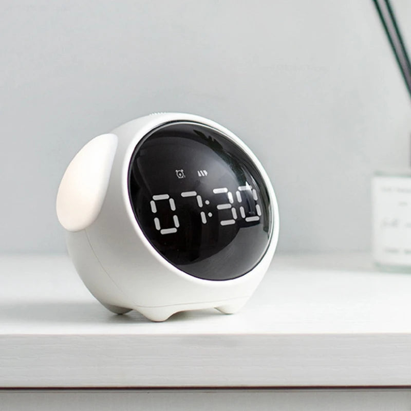 A white digital alarm clock with a round display showing 07:30 sits on a white surface.