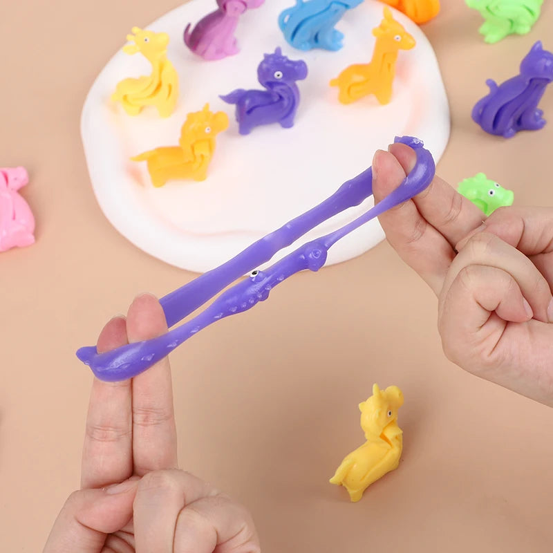 A hand holds a purple sensory stress bracelet next to various colored dinosaur and animal figurines on a white plate.