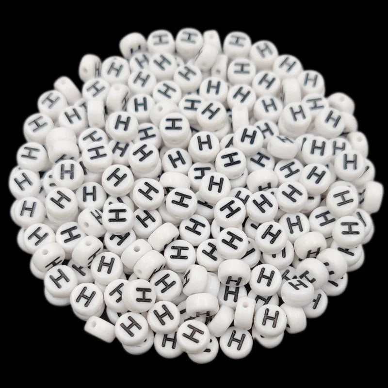 A pile of small white acrylic alphabet letter beads for jewelry making