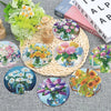 A collection of eight diamond painting coasters featuring floral designs and various colors, displayed on a woven mat.