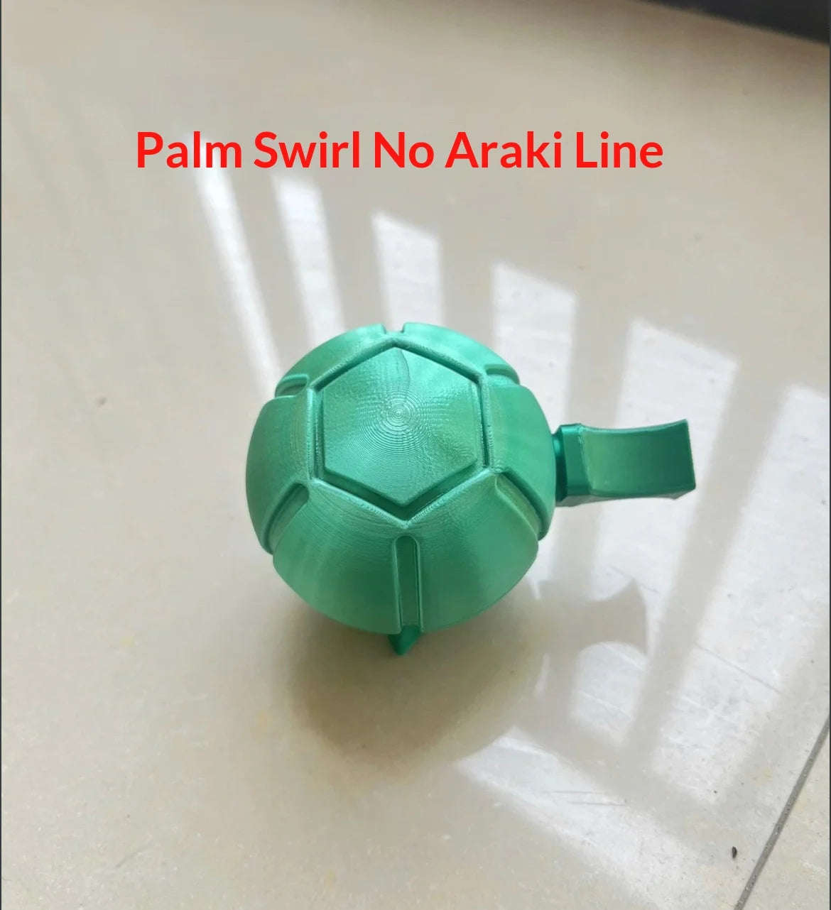 A teal steel ball fidget toy with a green handle, used for stress relief.