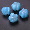 Several small, light blue glass charm pendants shaped like flowers are scattered on a dark surface.