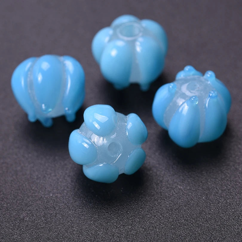Several small, light blue glass charm pendants shaped like flowers are scattered on a dark surface.
