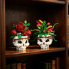 A set of gothic skull floral building blocks featuring red roses and green foliage displayed on a wooden shelf.