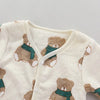 A cream-colored fleece jacket with a brown bear print and a green scarf detail.