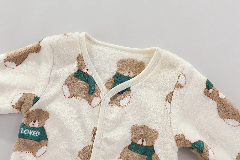 A cream-colored fleece jacket with a brown bear print and a green scarf detail.