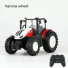 A white and red remote control tractor model with large tires is shown next to a game controller.