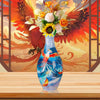 Blue and white porcelain flower vase with a floral arrangement displayed in front of a vibrant red and orange feathered backg