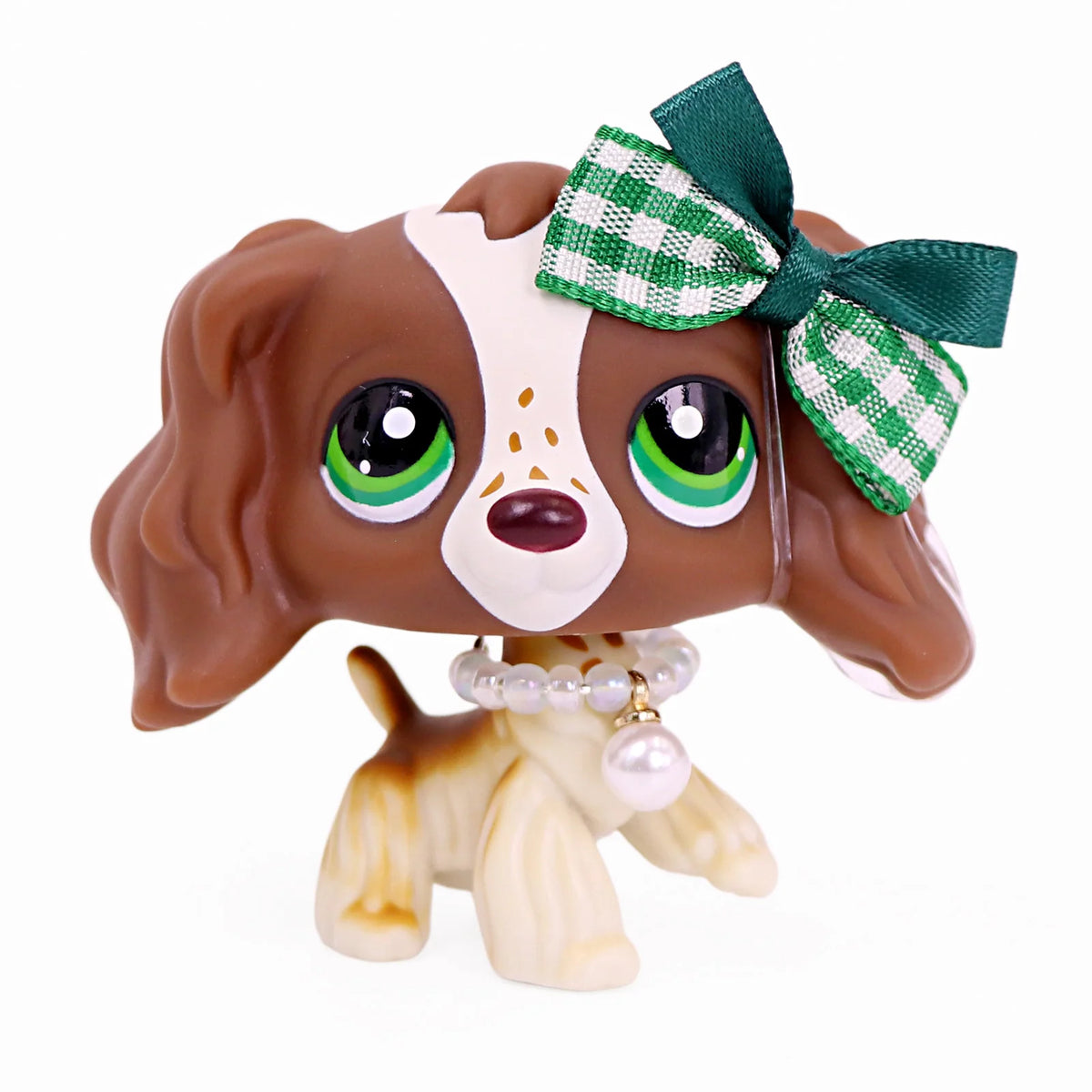 A brown miniature pet animal figure with large eyes and a green checkered bow and pearl necklace.
