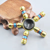 A metal fidget spinner with a rainbow finish is displayed on a wooden surface.