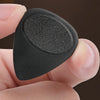 A hand holds a black guitar pick with an anti-slip grip, showing its shape and texture.