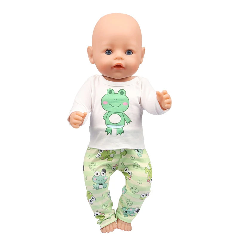 A baby doll wearing a white shirt with a green frog graphic and matching light green patterned pants.