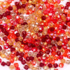 A close-up view of small, faceted crystal bicone glass beads in shades of red, orange, and amber.