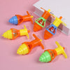 A collection of glow-in-the-dark spinning tops in various colors like orange, yellow, and green, displayed on a pink backgrou
