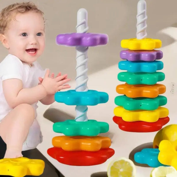 A baby is interacting with a colorful spinning rainbow stacking tower made of plastic rings.