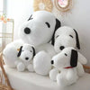 A white plush toy resembling a dog with black ears and eyes, sitting on a white surface.