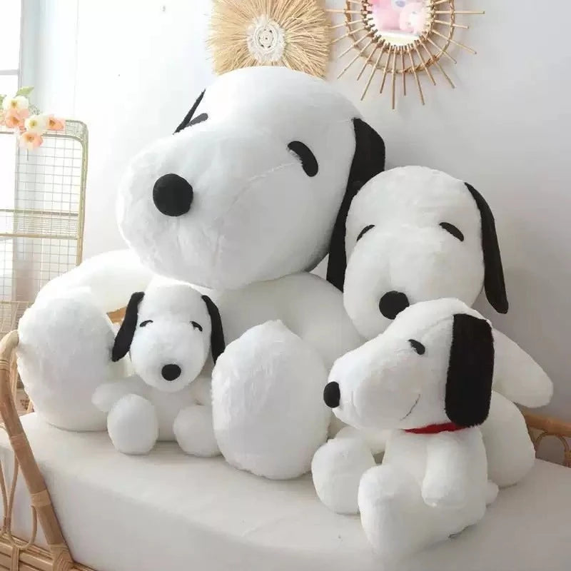 A white plush toy resembling a dog with black ears and eyes, sitting on a white surface.