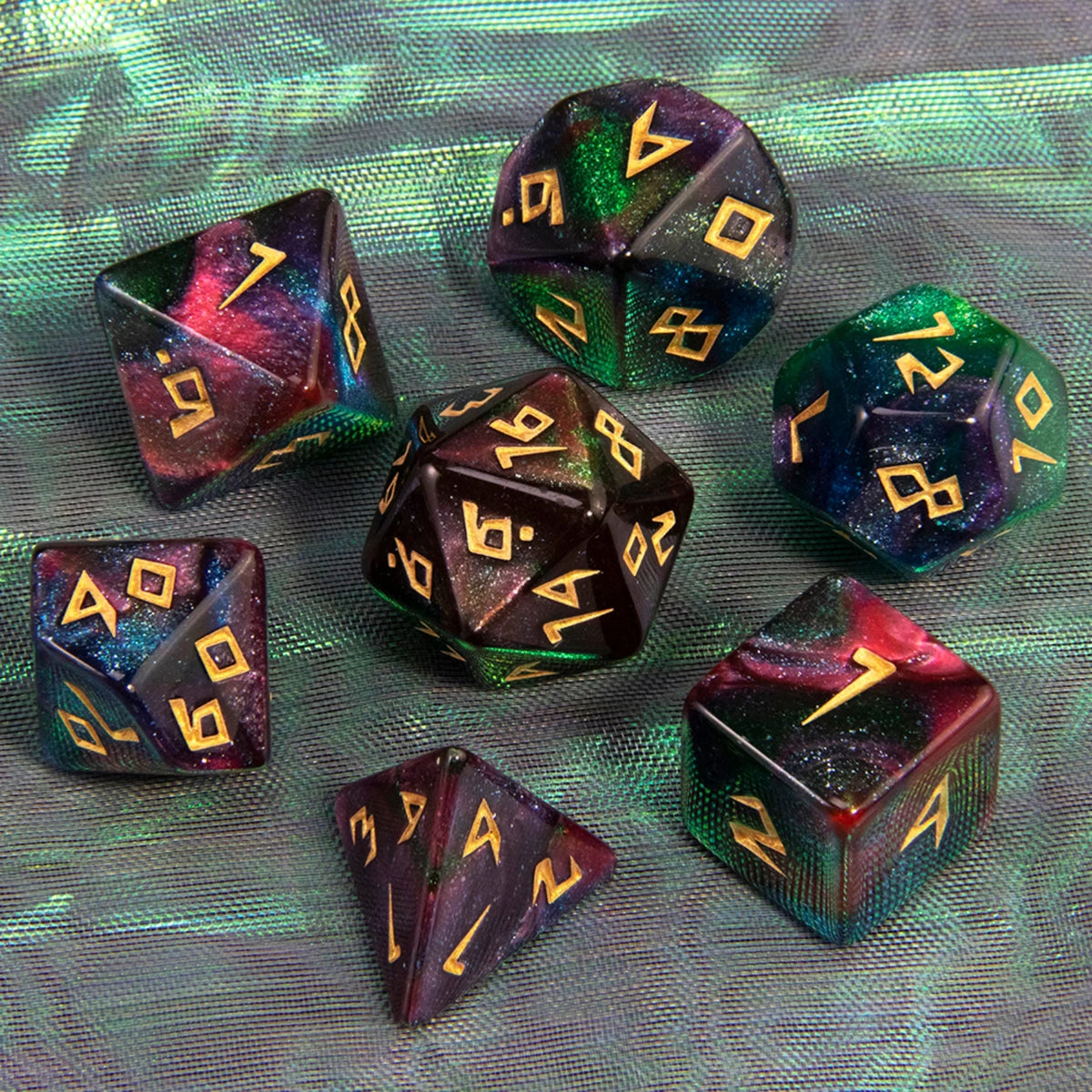 A collection of seven glitter polyhedral dice in various colors and angles resting on a green fabric surface.