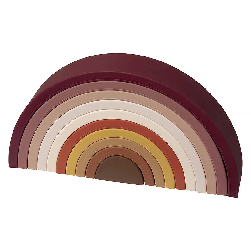 A row of soft silicone rainbow building blocks in various muted earth tones and pinks, arranged in a semi-circle.