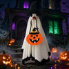 A white ghost costume with a pumpkin face hangs in front of a dark, spooky house with glowing lights and pumpkins.
