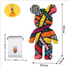 Buntes Teddybär-Bausteinfigur mit schwarz-weißen Mustern neben seiner Verpackung.